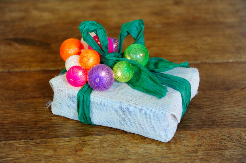 Un pacchetto di Natale con palline colorate luminose juta